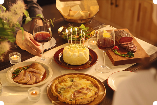 ディナーテーブルの画像 中央にケーキ ピザやお肉が並んでいる